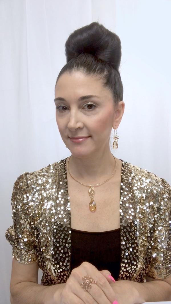 Designer, Lisa Ramos showcasing a the necklace in gold and matching earrings.  