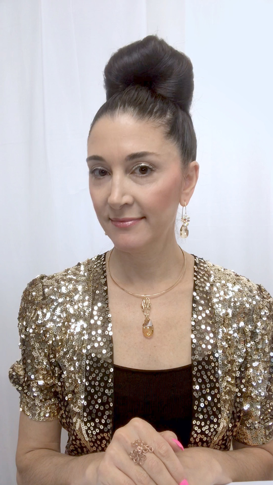 Designer, Lisa Ramos showcasing a the necklace in gold and matching earrings.  